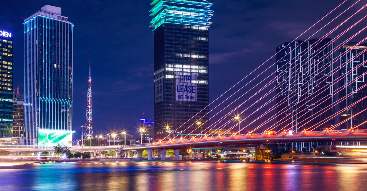 Colorful urban night scene showcasing a brightly lit bridge and modern city skyline reflecting on water.