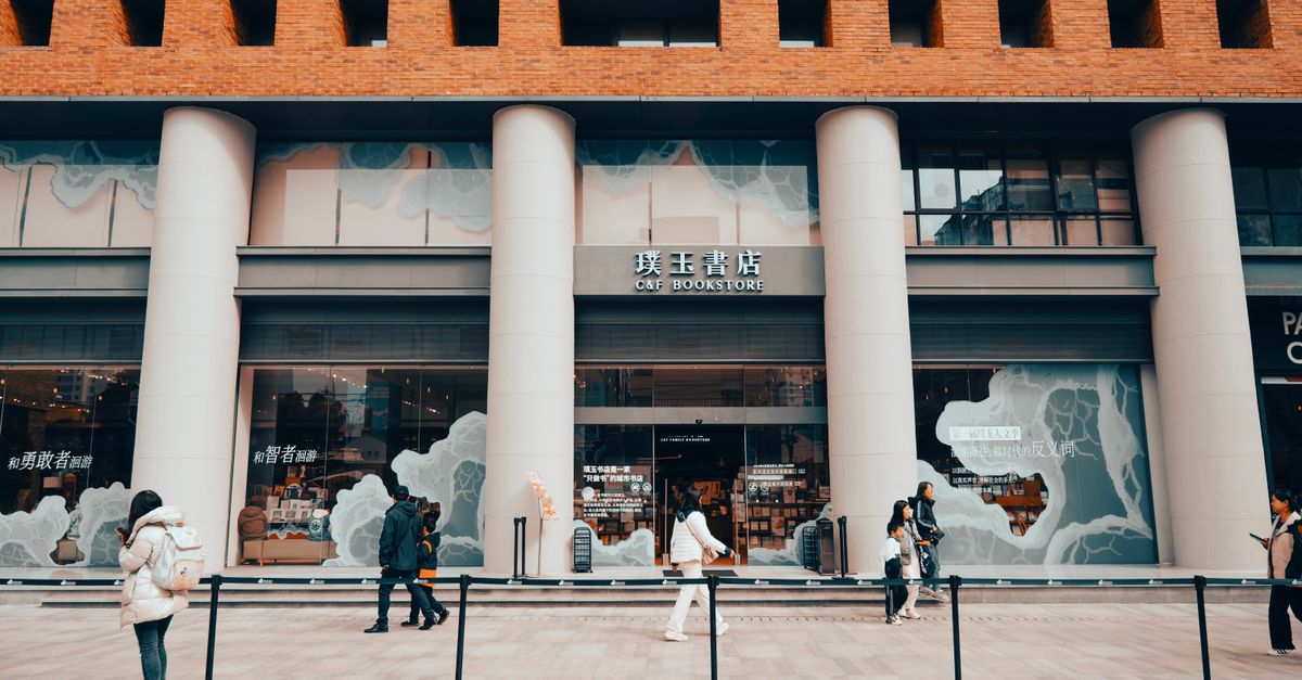People walking by a modern bookstore with columns in a city setting.