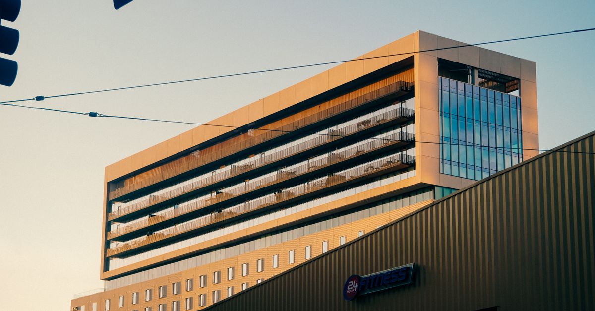 A modern office building exterior photographed at sunset, featuring a gym sign.