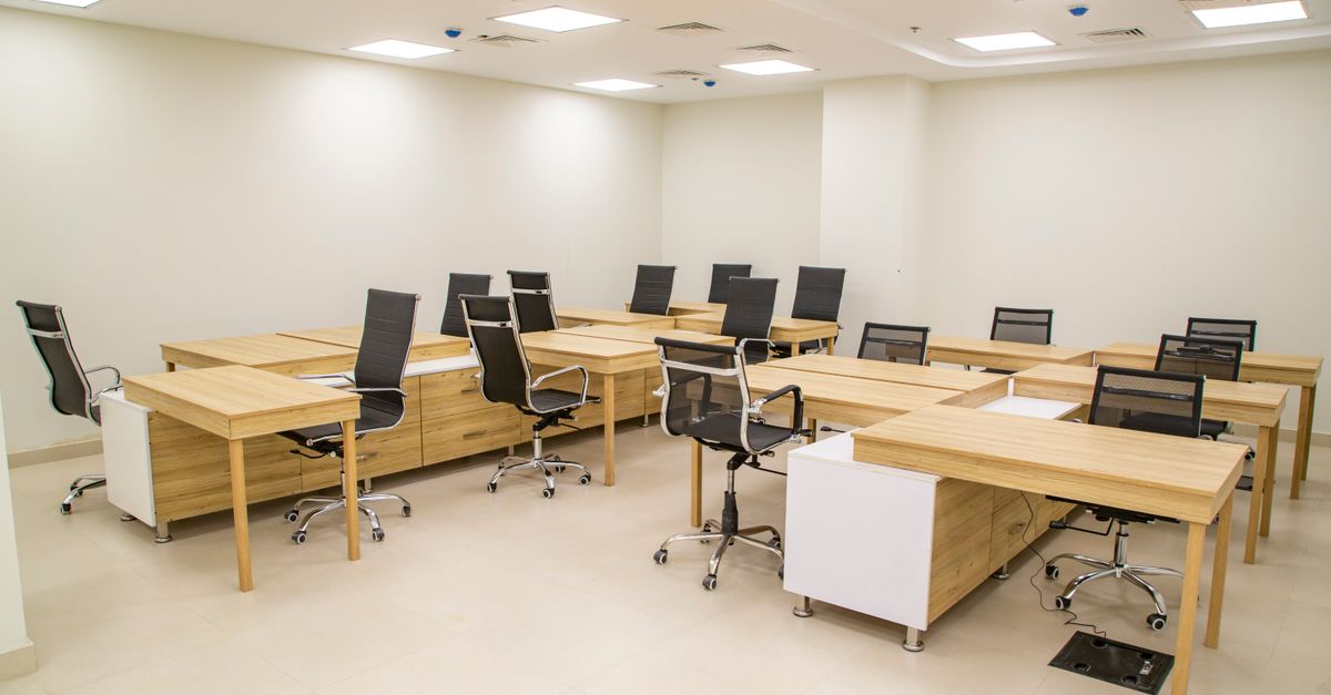 Spacious modern office with wooden desks and ergonomic chairs, ideal for team workspace.