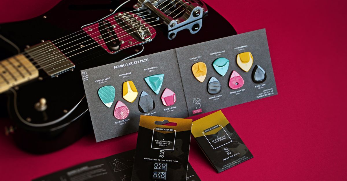 Vibrant still life of Rombo guitar picks variety pack and electric guitar on a red backdrop.