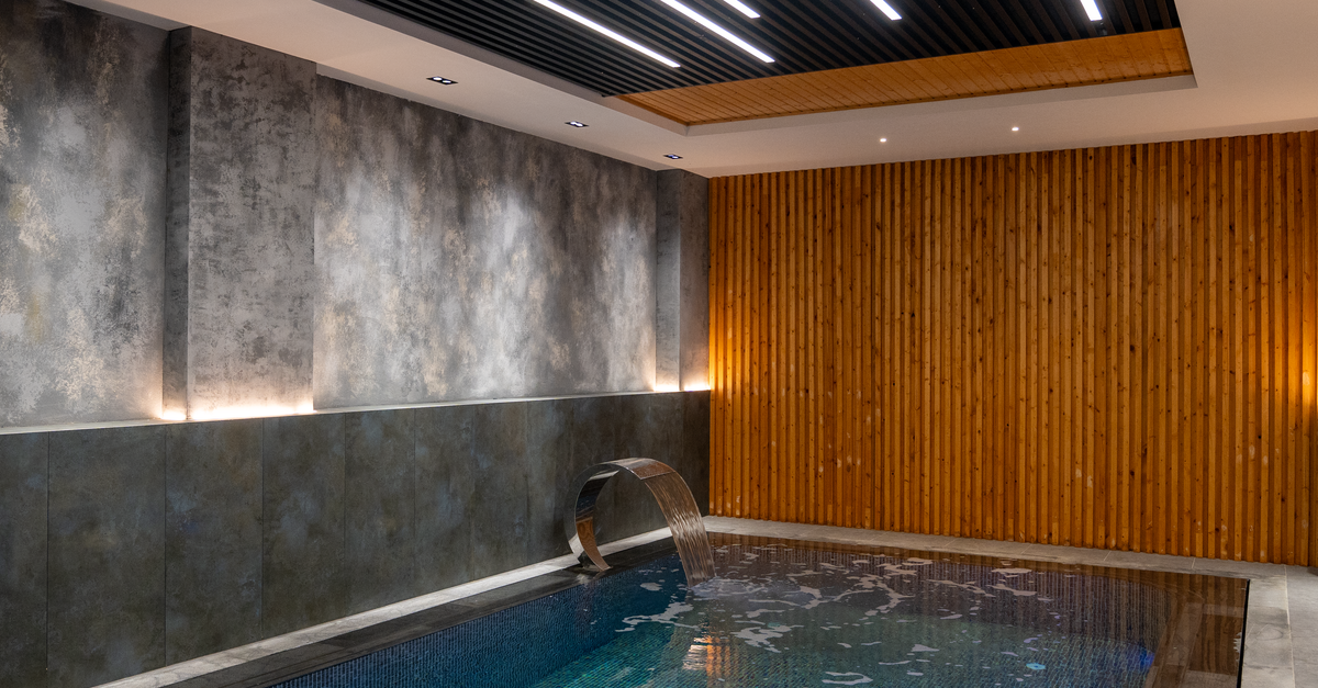 Relaxing indoor pool area featuring modern lighting and elegant wood paneling design.