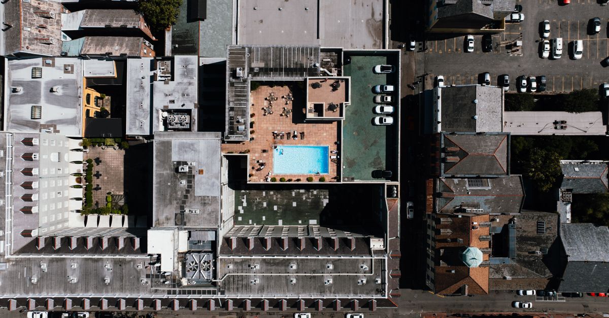 Aerial shot capturing urban rooftops with a pool and parking lot in New Orleans.