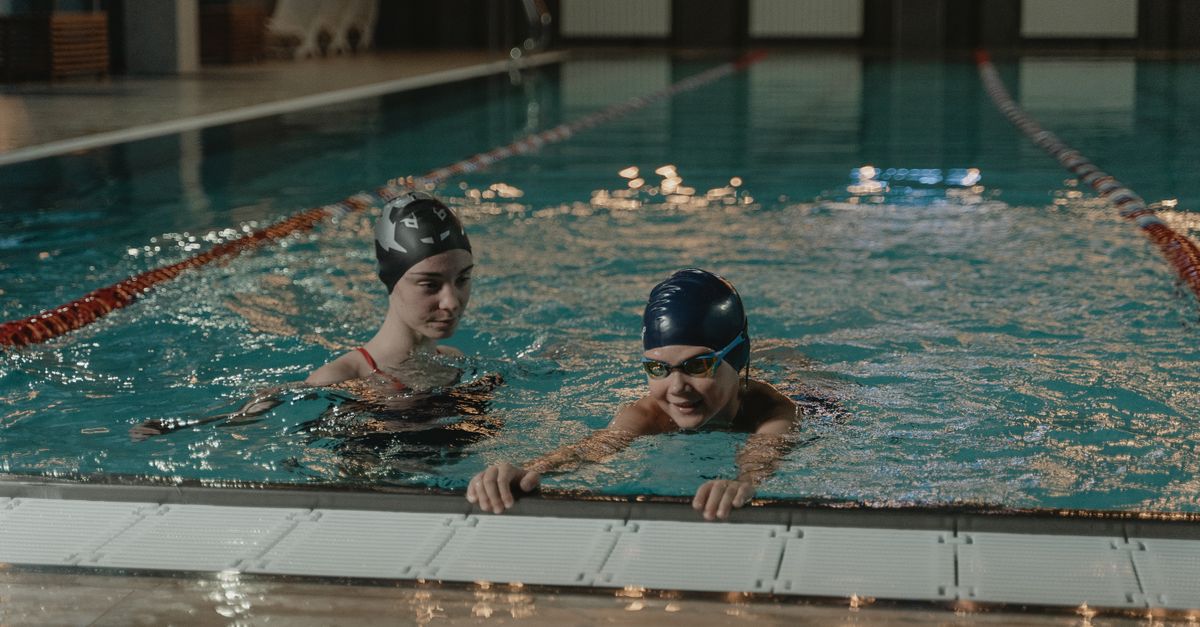 Two swimmers training in an indoor pool, focused and determined.
