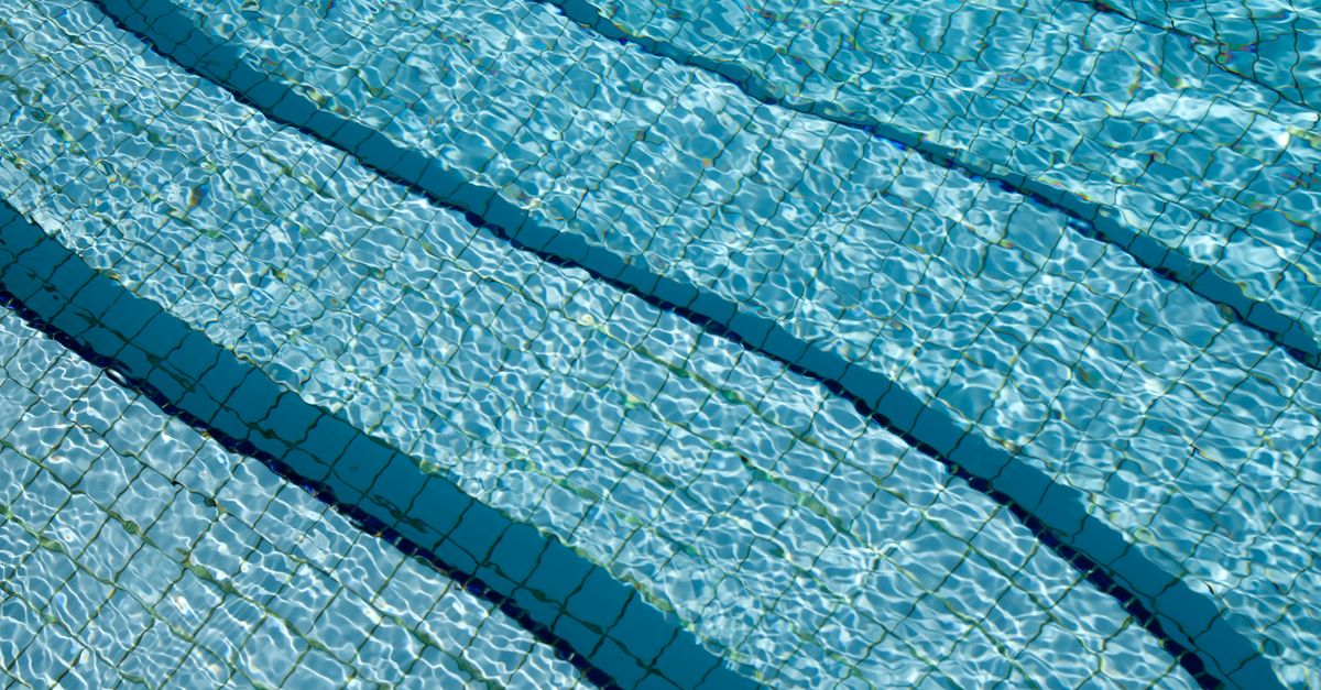 A detailed view of crystal clear swimming pool water over a tiled surface, showcasing its calm and refreshing nature.