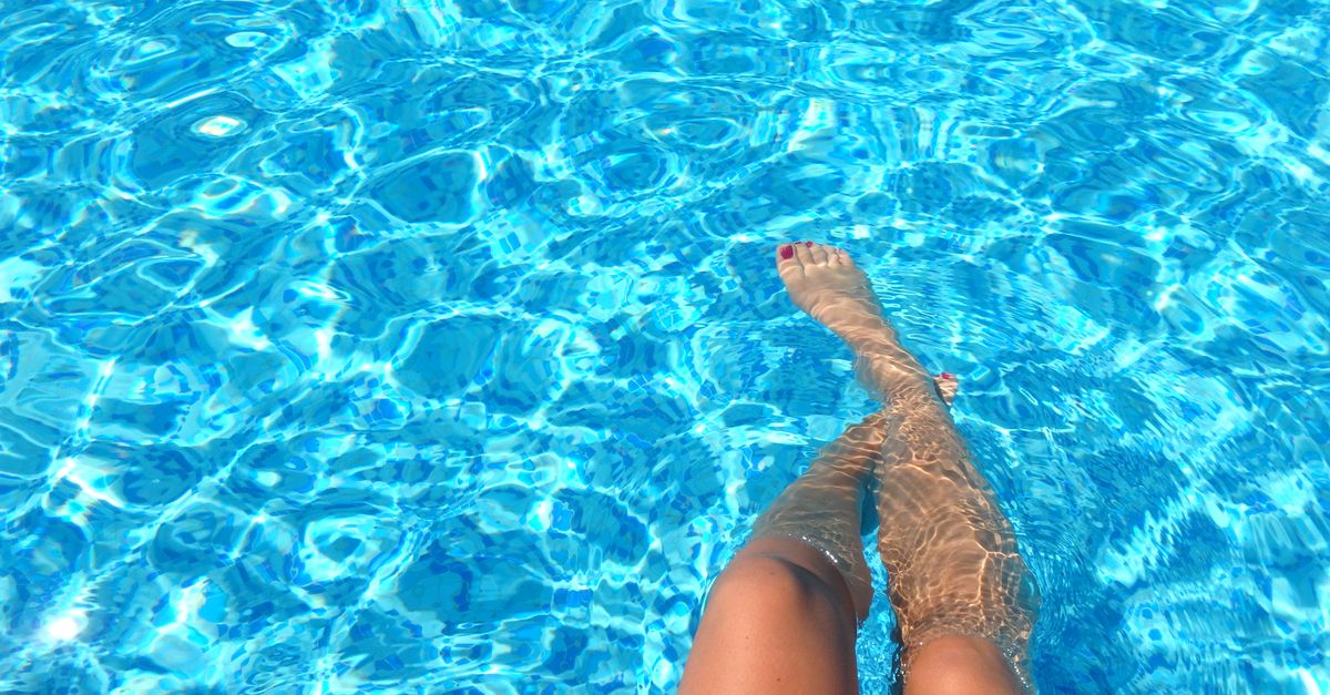 A person relaxes in a swimming pool with clear blue water, capturing summer vibes.