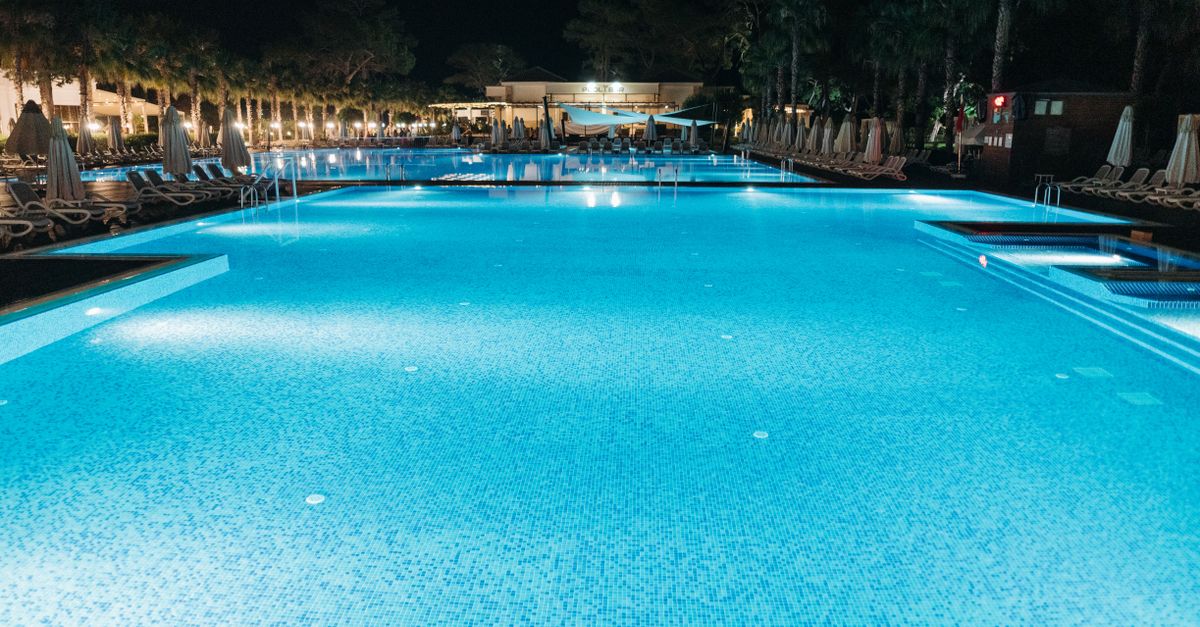 A luxurious resort swimming pool illuminated at night, offering a serene and elegant ambiance.