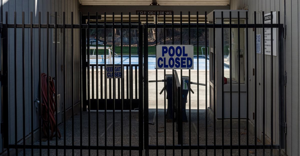 Iron gate blocking a closed community pool entrance with a clear sign.