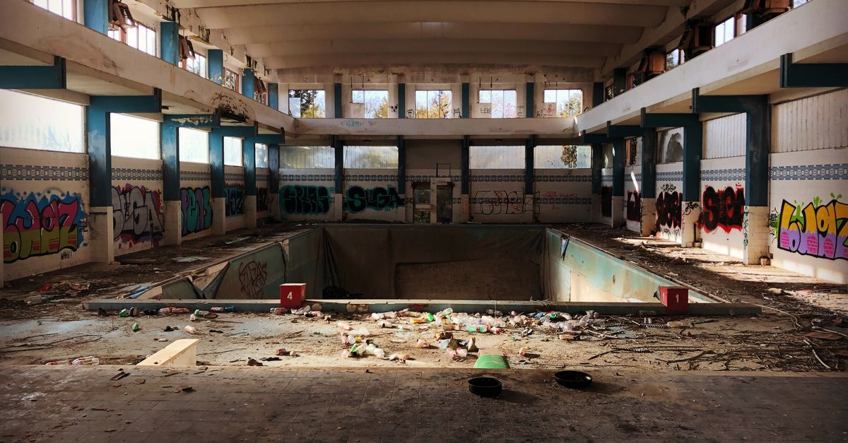 Explore this eerie, abandoned indoor pool in Foggia, Italy, filled with graffiti and debris.