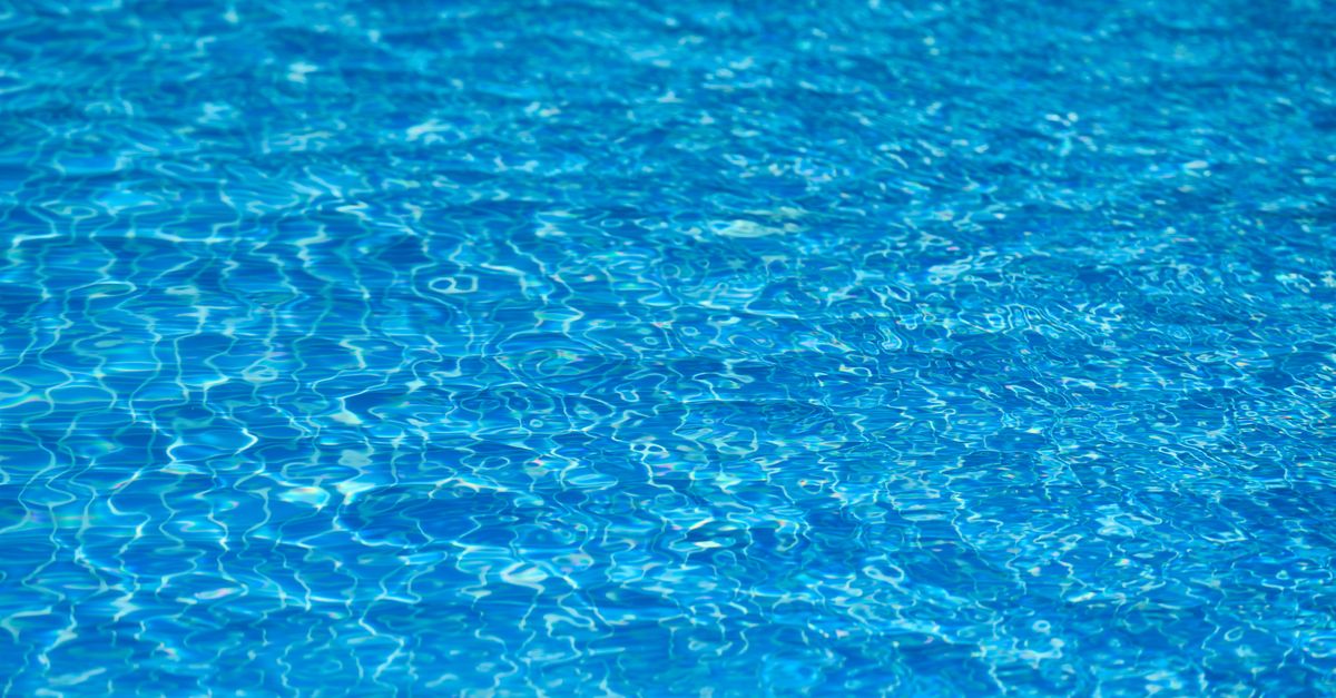 Bright and clear blue water texture in a swimming pool under sunlight.