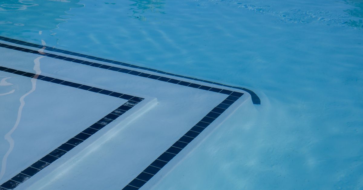 Serene view of a clear blue swimming pool with tiled steps and shimmering water.