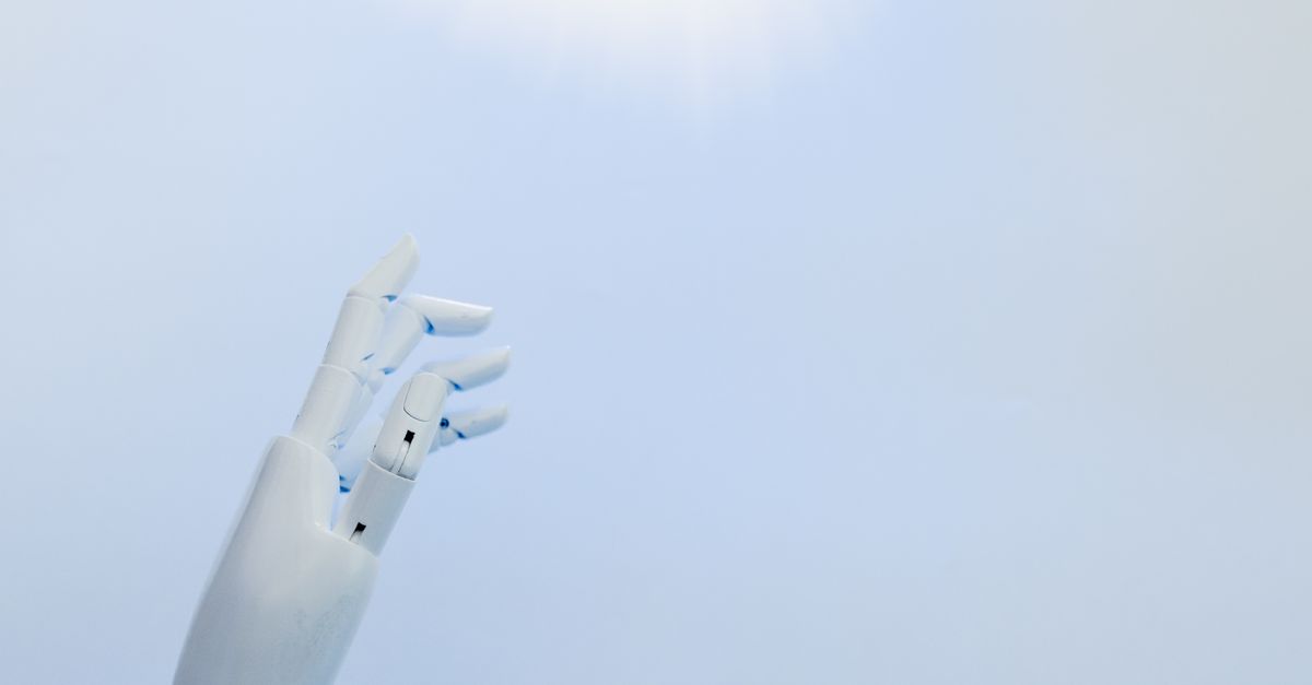 A robotic hand reaching towards a bright light on a white background symbolizing innovation.