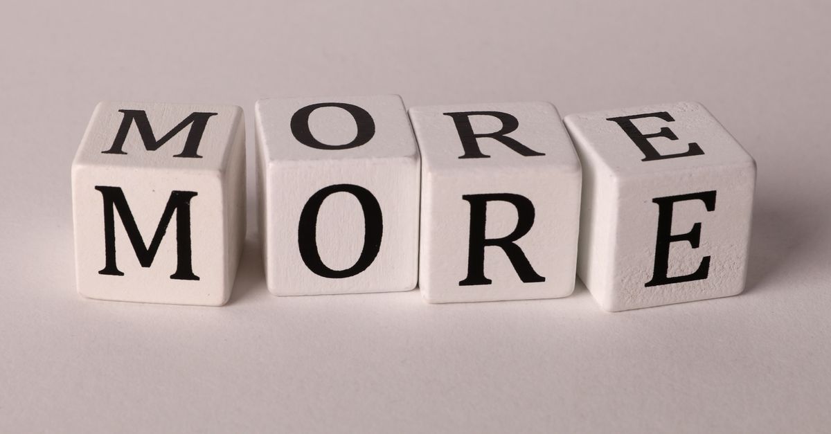 Close-up view of four dice with letters spelling MORE on a white background.