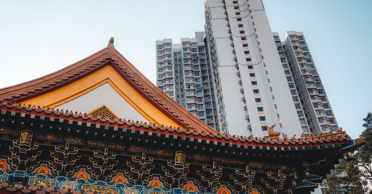 Ancient temple architecture contrasted with modern skyscraper in Hong Kong.
