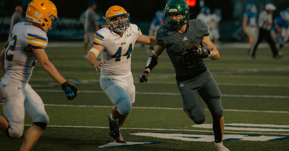 High school football players in action during an evening game under stadium lights.