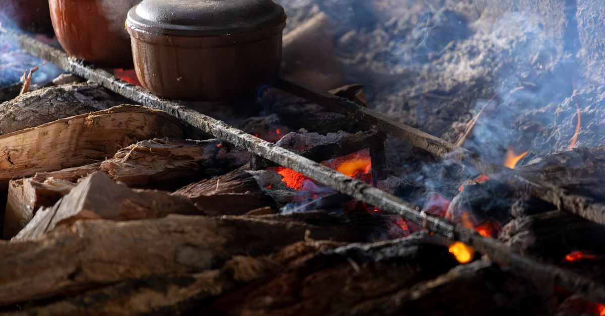 Traditional Vietnamese clay pots cooking over open wood fire, showcasing rustic culinary techniques.