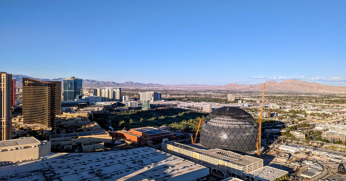 A breathtaking aerial view of Las Vegas with a prominent sphere-shaped landmark and clear blue skies.