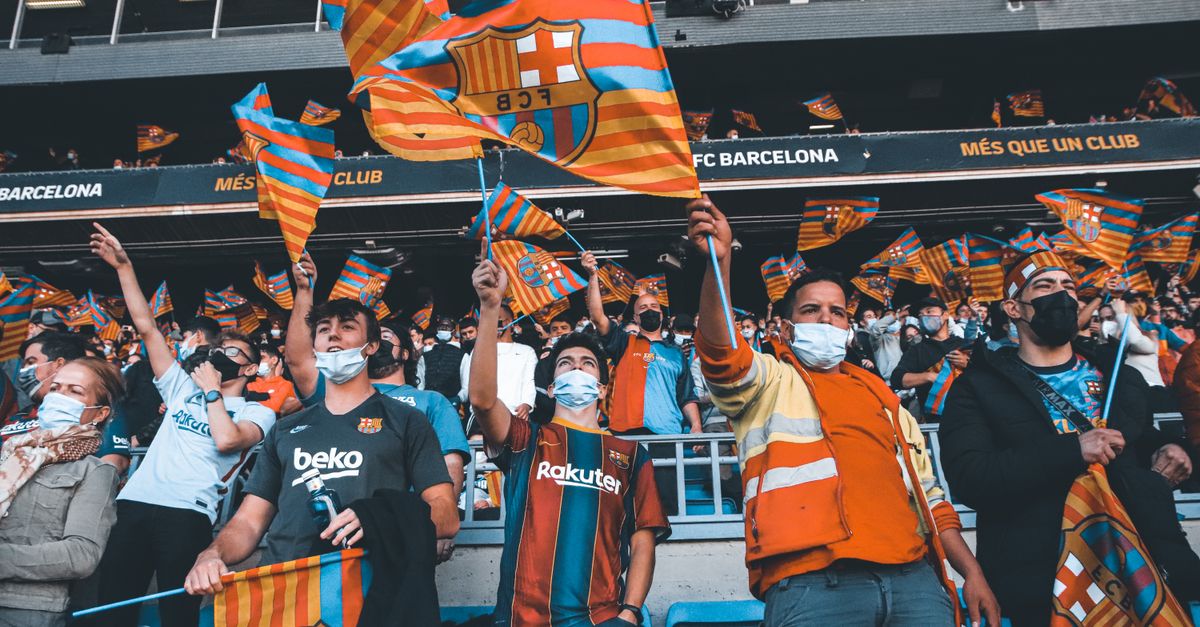 Fans enthusiastically wave FC Barcelona flags at a football match, showcasing team spirit and unity.