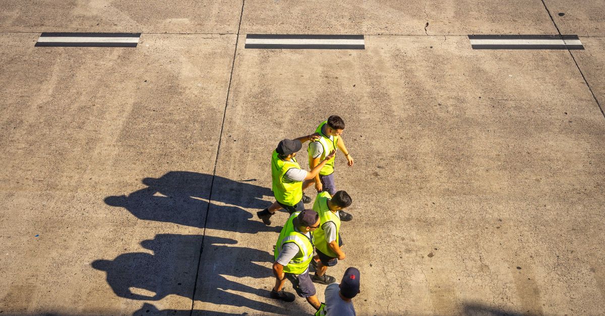 Aerial view of airport workers walking on the tarmac in Buenos Aires on a sunny day.