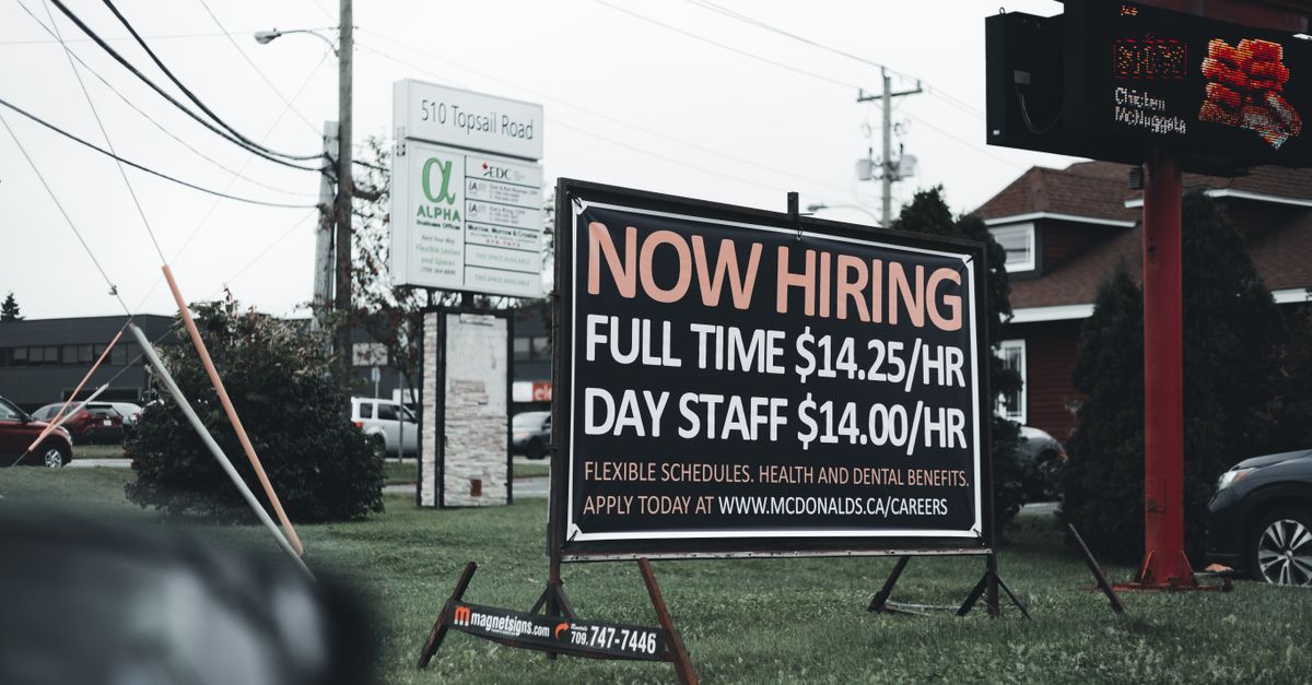 Outdoor hiring sign advertising restaurant job openings with competitive wages and benefits.