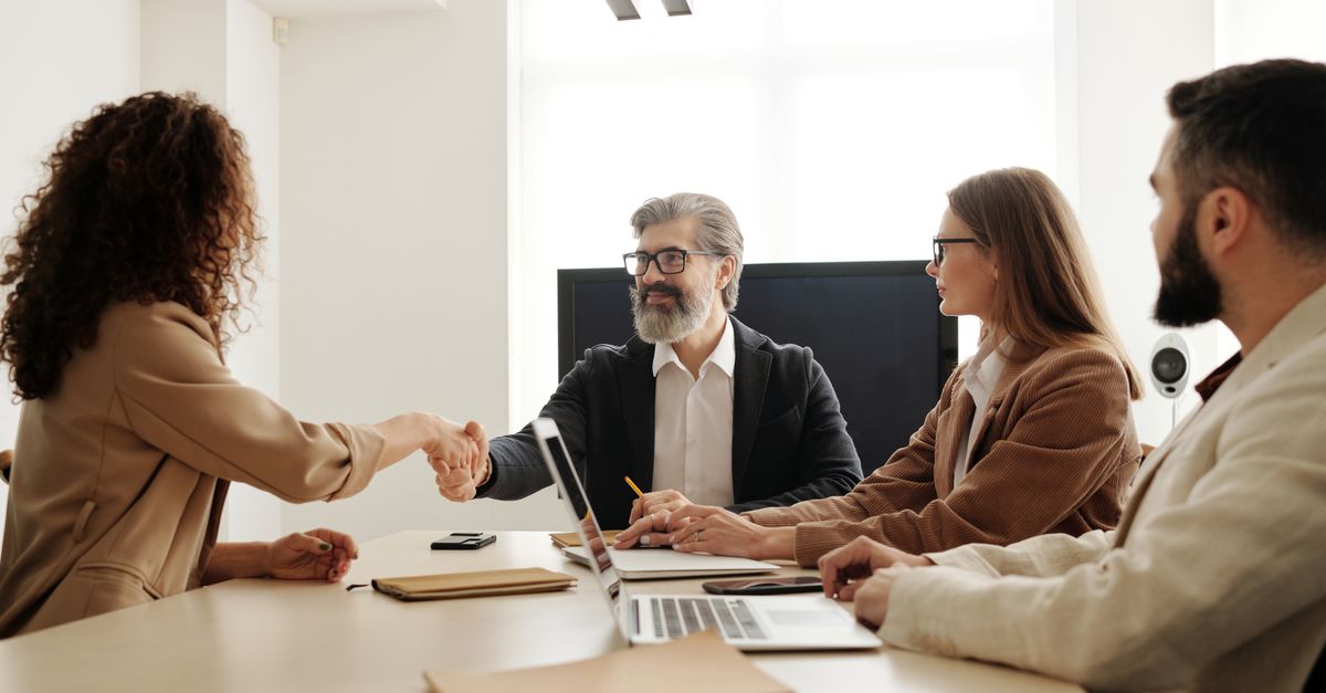 Colleagues in an office celebrating a successful negotiation with a handshake.