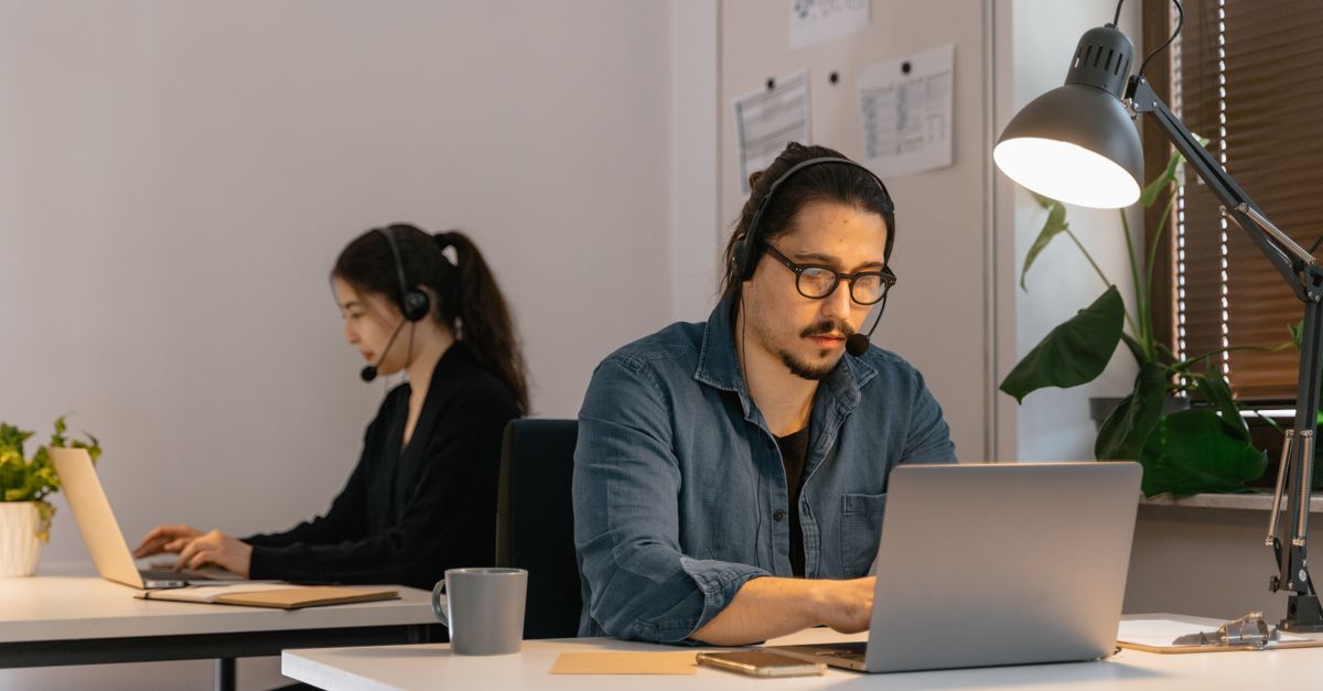Two call center employees working diligently with headsets in the office.