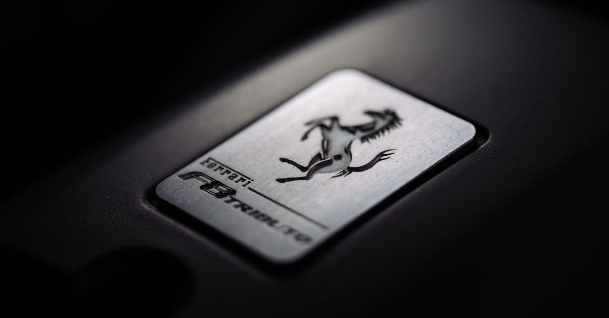Close-up of a metallic car logo badge with a prancing horse, symbolizing luxury and speed.
