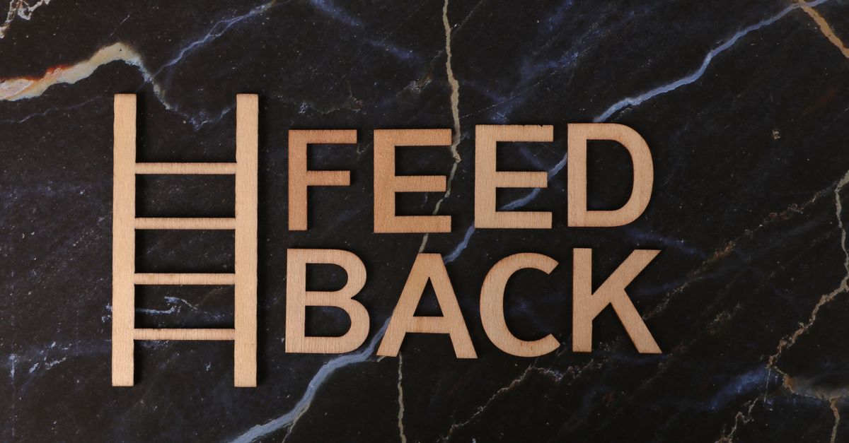Wooden letters spelling 'Feedback' arranged creatively on a marble surface.