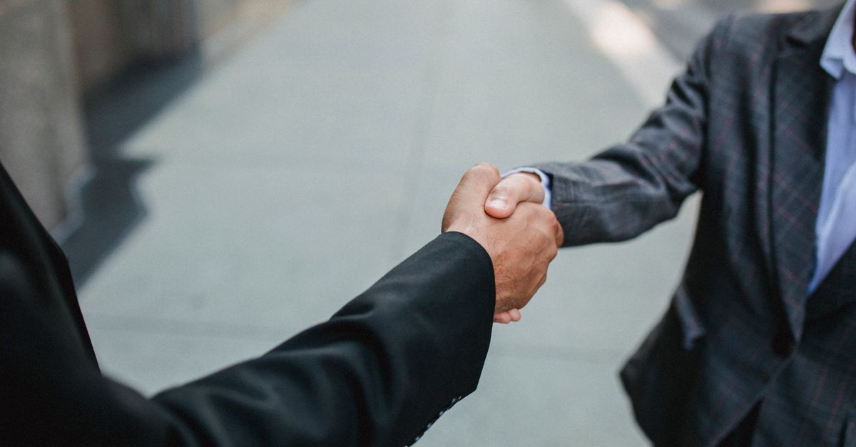 Close-up of two businessmen shaking hands outside, symbolizing partnership and agreement.