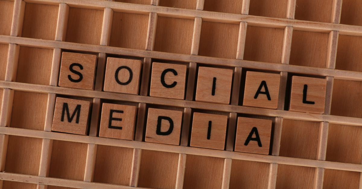 Close-up of wooden letter blocks spelling 'Social Media' on a wooden grid.