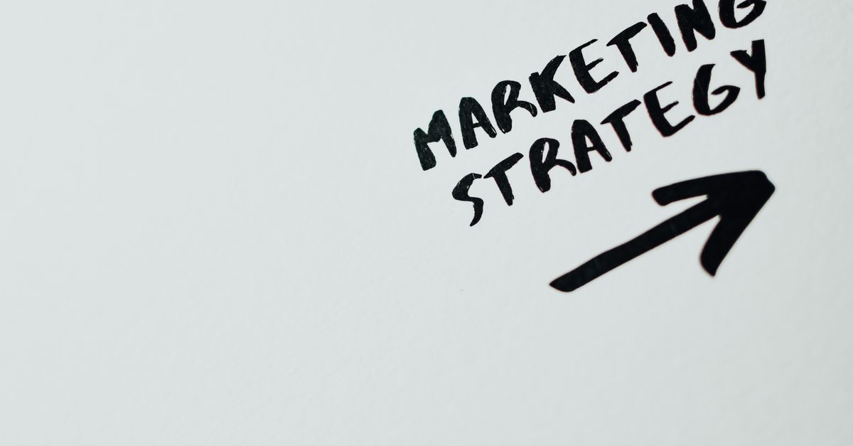 Close-up of handwritten 'Marketing Strategy' text with an arrow on white background.