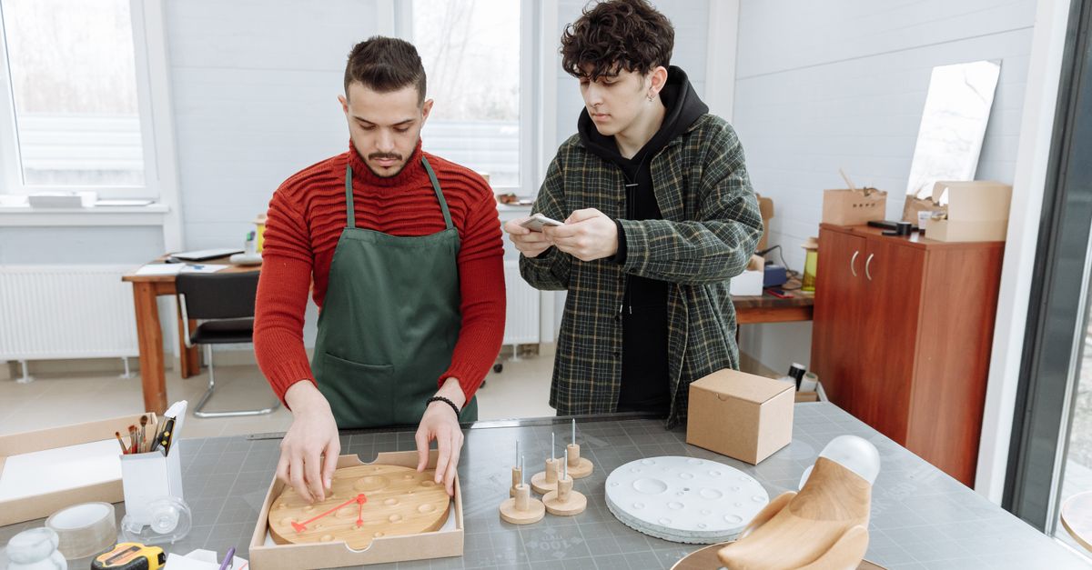 Two men in a creative workspace assembling clocks, capturing industrial and craft elements.