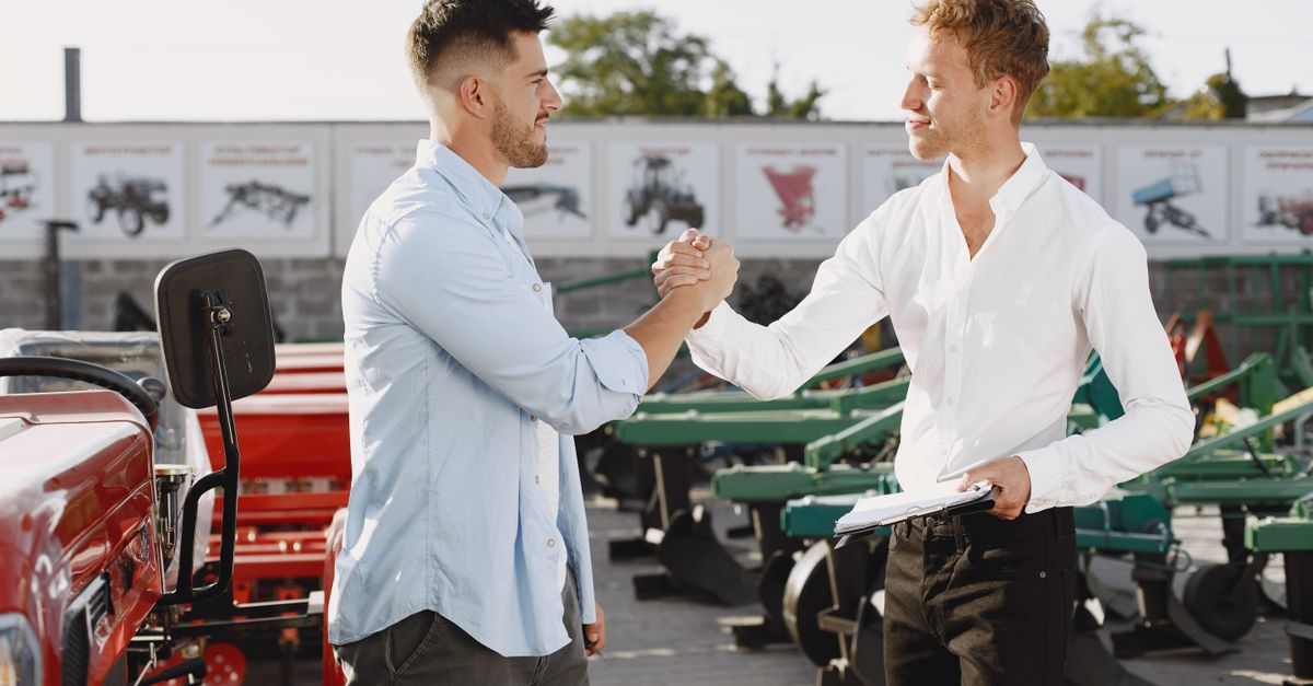 Two businessmen shaking hands outdoors, signaling a successful deal.