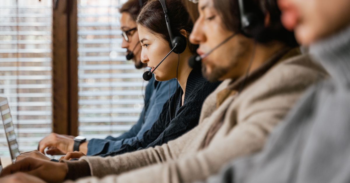 Focused customer support team using headsets and laptops in a busy office setting.