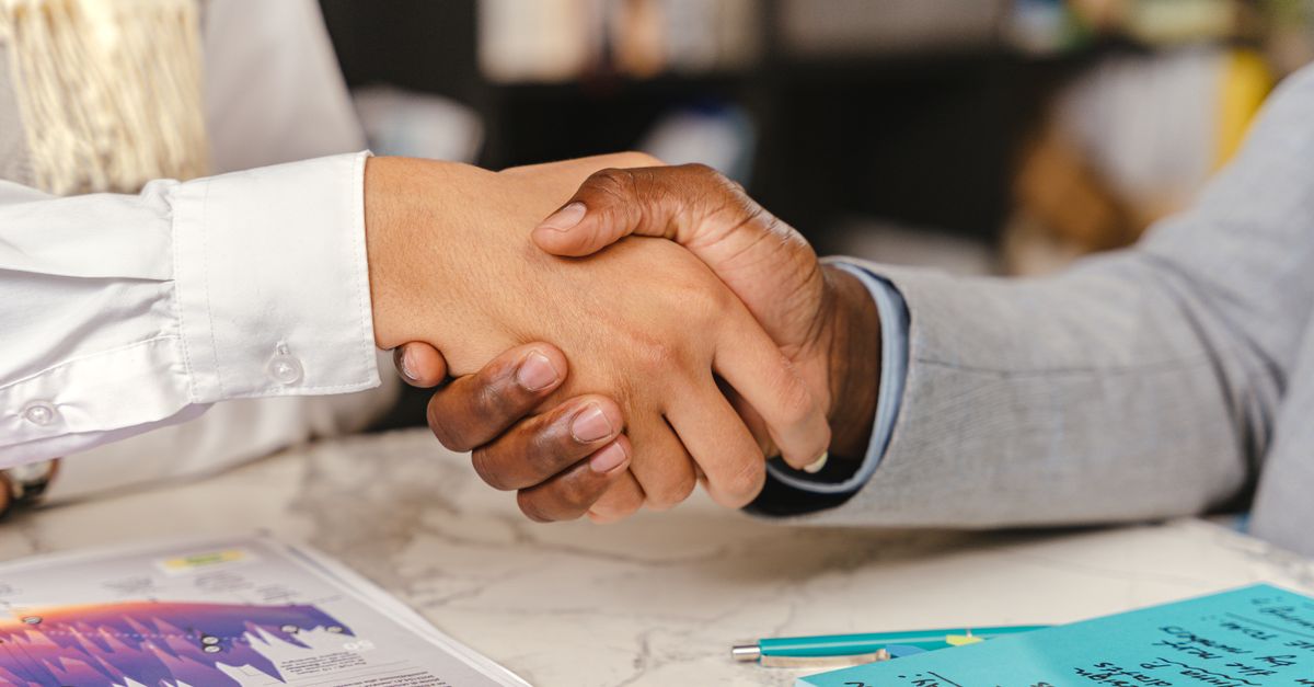 Close-up of a business handshake between two professionals over an office desk with documents.