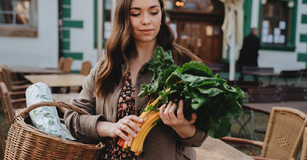 Young woman with a basket shopping for fresh vegetables outdoors in Erfurt, Germany.
