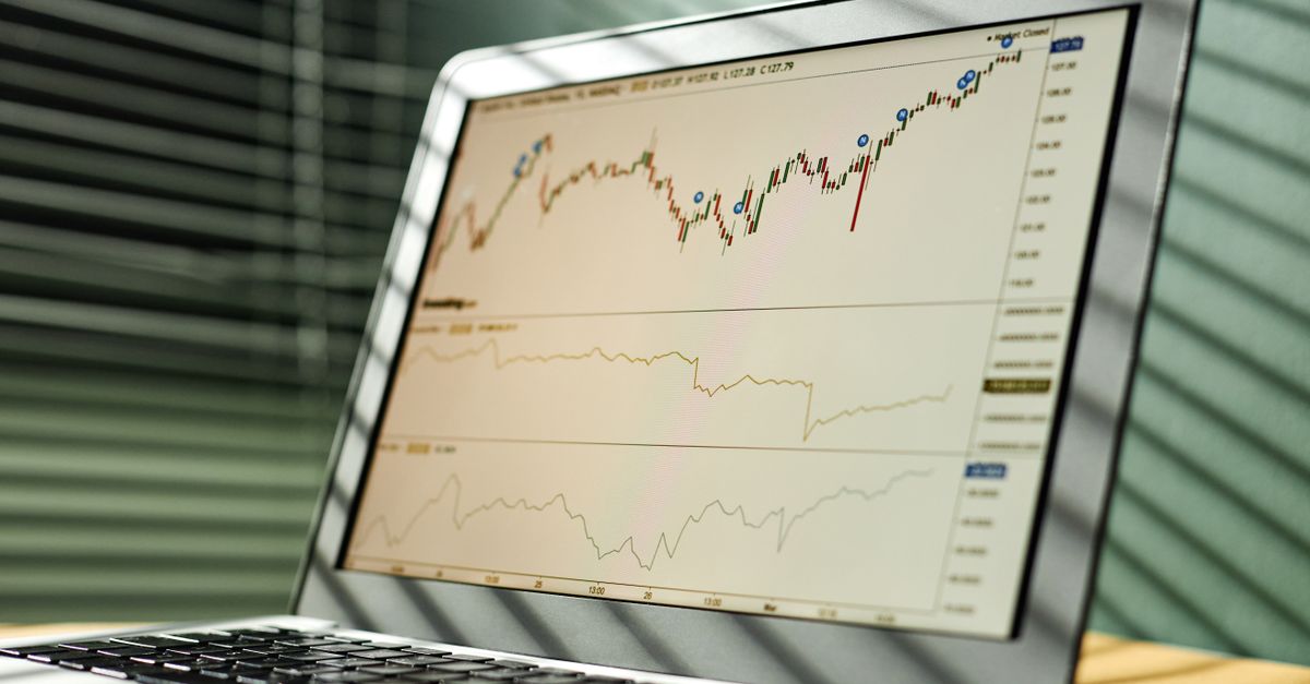 Close-up of a laptop displaying stock market data and graphs in an office setting.