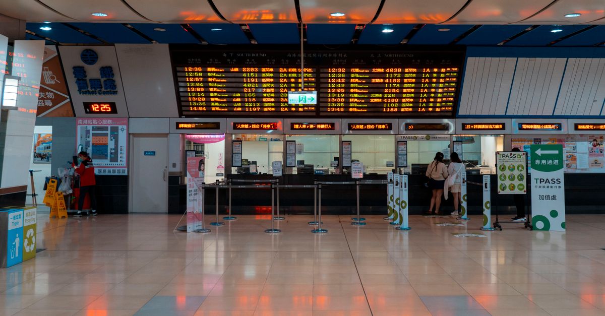 Interior of a train station with a digital timetable and ticket counters.