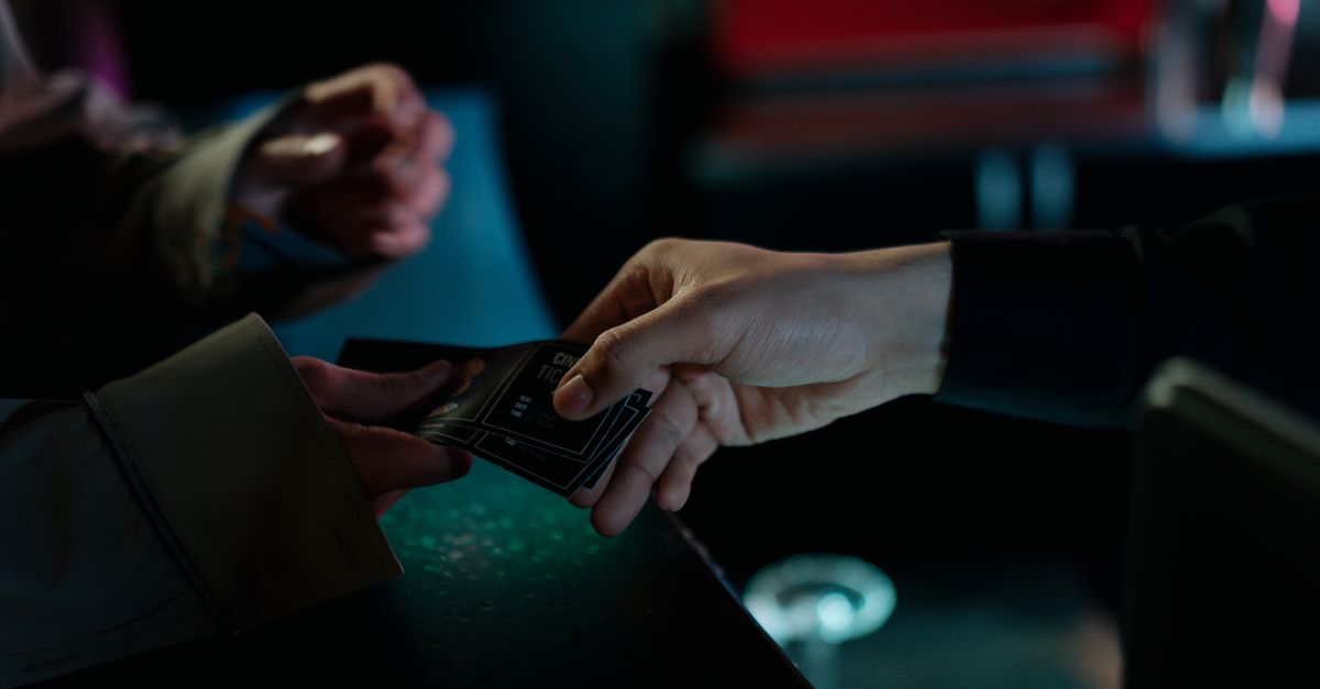 Hands exchanging movie theater tickets indoors, capturing a cinematic moment.