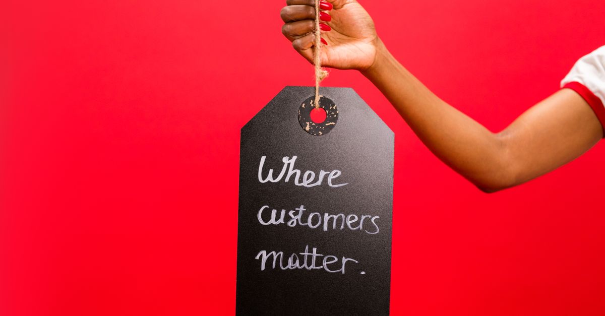 A hand holding a tag with 'Where customers matter' text on a vivid red background, emphasizing customer service.