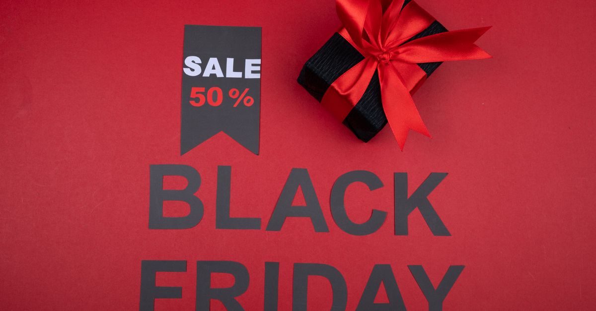 Black Friday sale banner with 50% off tag and gift box wrapped with red ribbon on red background.