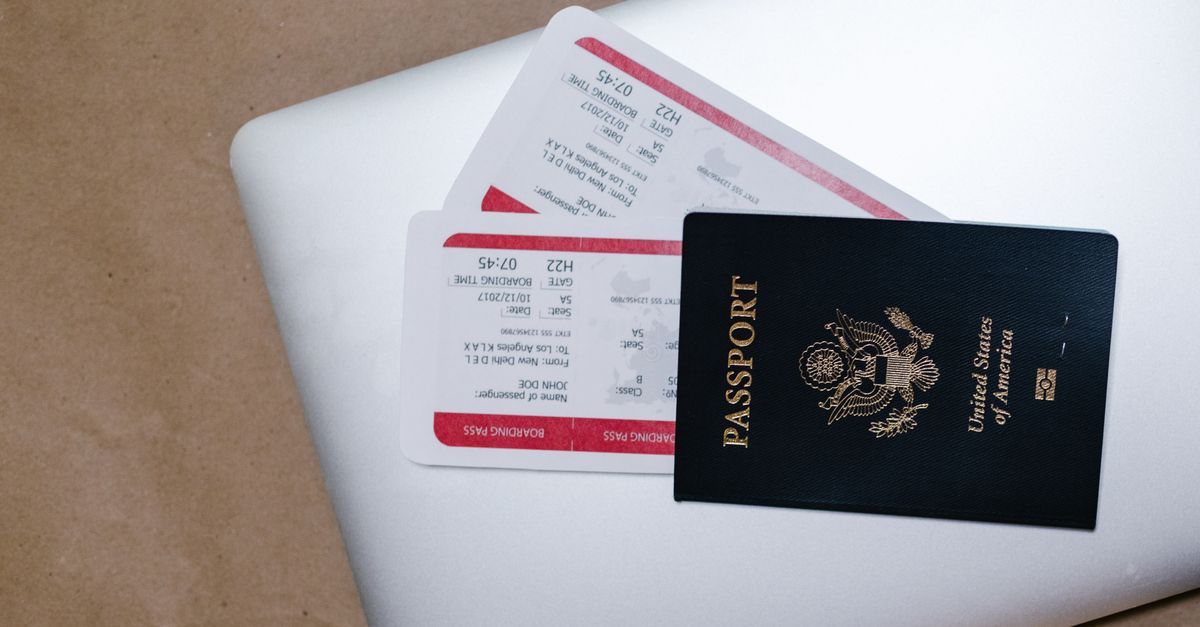 Close-up of a passport and boarding passes on a laptop, symbolizing travel preparation.