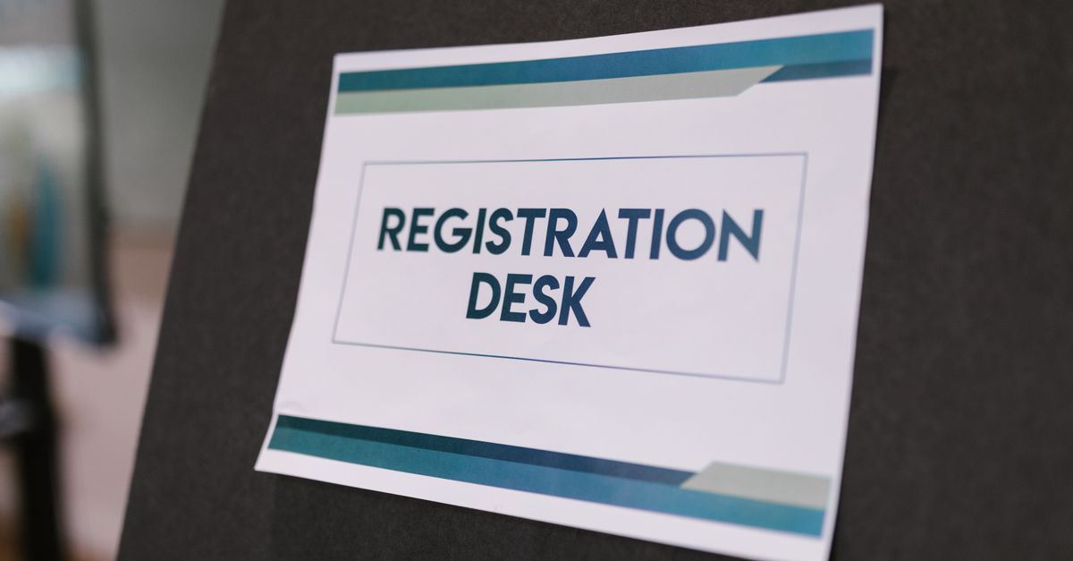 A close-up of a registration desk sign on a dark background.
