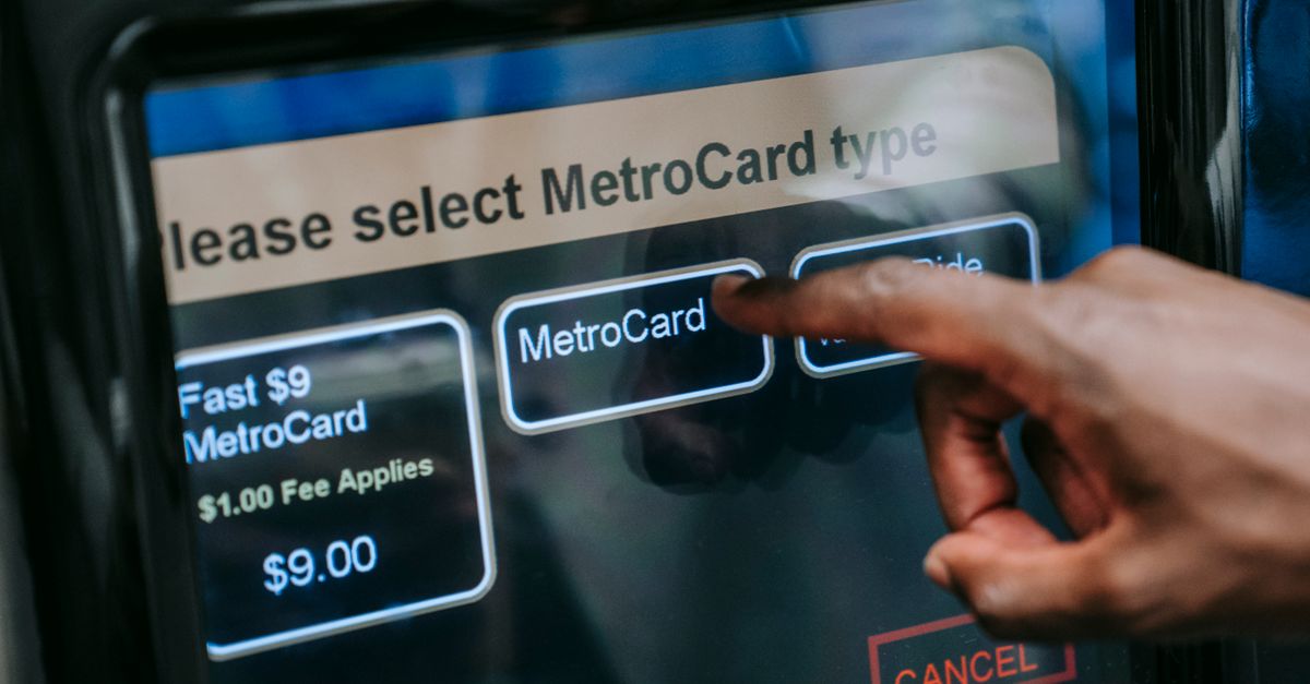 Close-up of a hand selecting a MetroCard type on a touchscreen in a subway station.