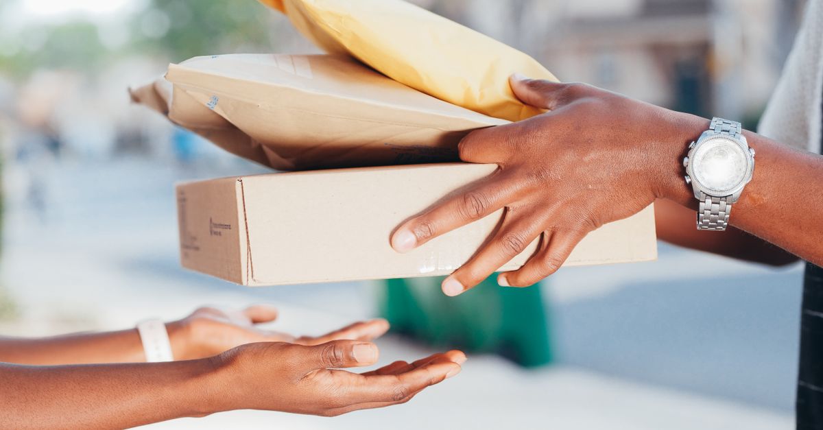 Close-up image of hands exchanging packages outdoors. Represents delivery and shipping services.