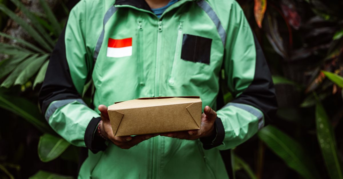 A delivery person in a green jacket holding a box, symbolizing fast delivery service.