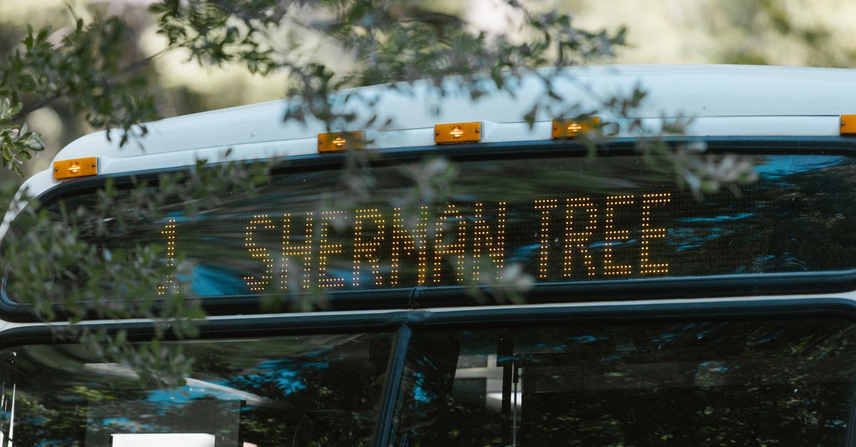 A public bus with a digital sign indicating Sherman Tree destination, amidst greenery.