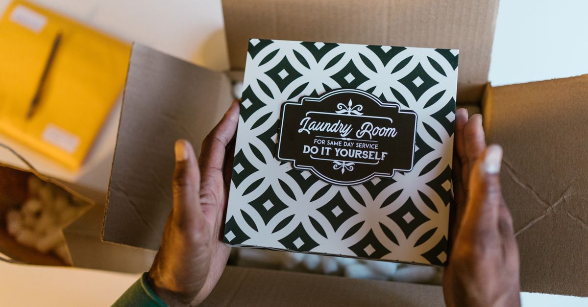 Card with 'Laundry Room' design held over an open box, perfect decor or DIY project inspiration.