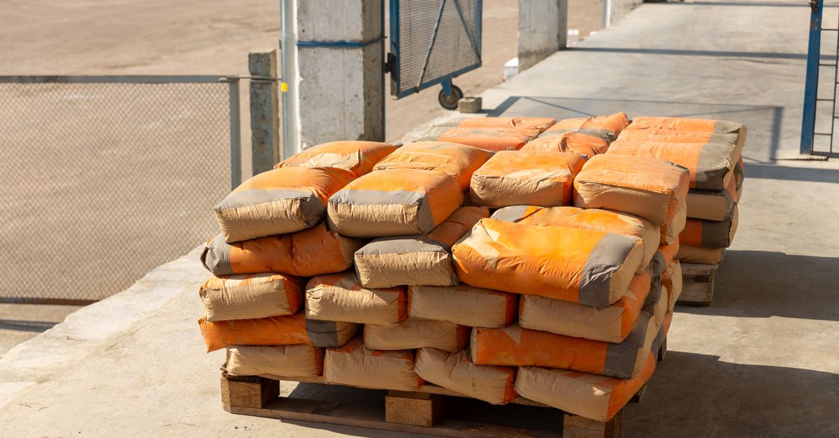 Pile of orange cement bags on a wooden pallet in an industrial setting.