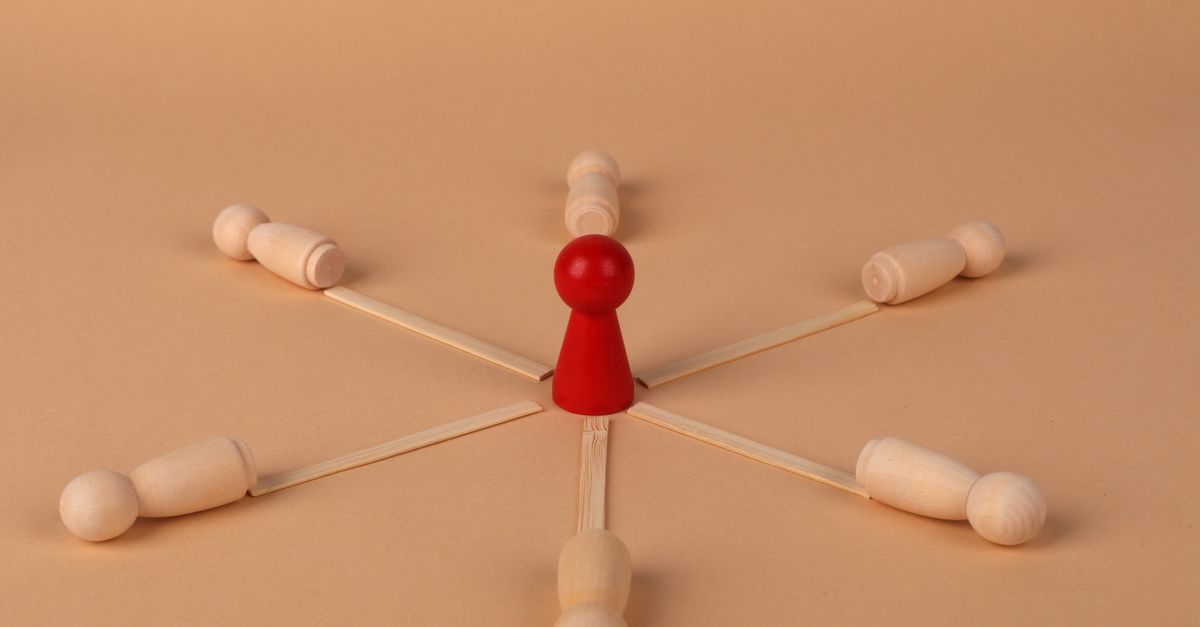 Red leader figure connected to wooden figures, emphasizing leadership and teamwork.